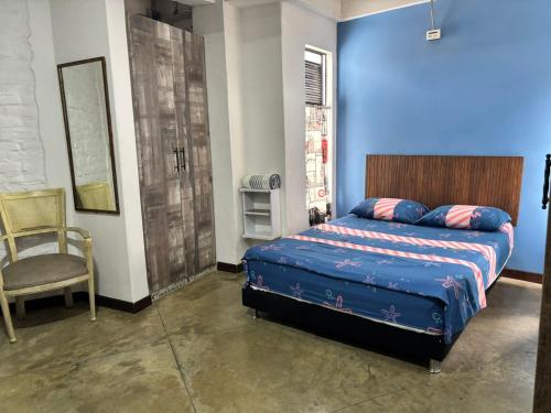 a bedroom with a bed and a chair and a blue wall at La Curva in Cali