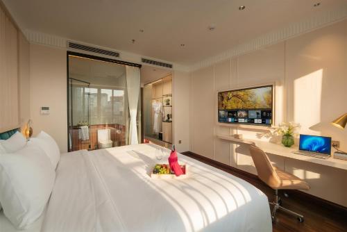 a bedroom with a large white bed and a desk at Luxeden Signature hotel in Hanoi