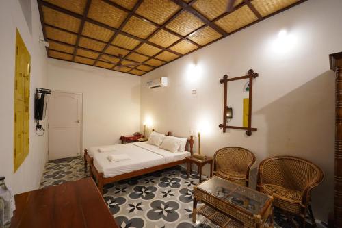 a bedroom with a bed and a table and chairs at Chettinadu Court- HERITAGE VIEW in Kānādukāttān