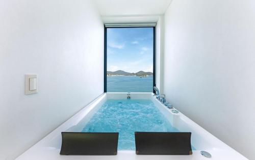 a room with a bathtub with a view of the ocean at Geoje Marepos Pension in Geoje
