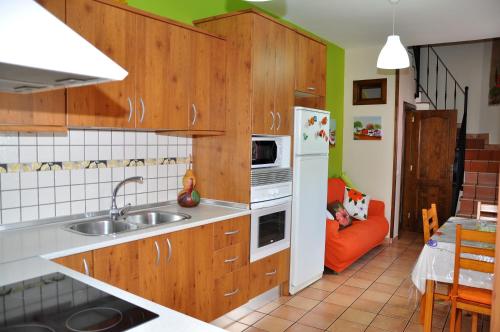 una cocina con armarios de madera y un sofá naranja en Casa Paco Las Vegas, en Valsequillo