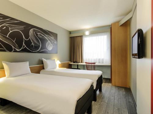 a hotel room with two beds and a tv at ibis Hotel Hannover City in Hannover