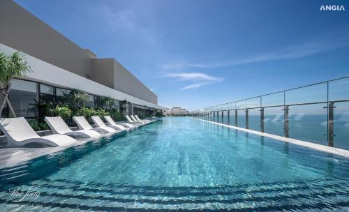 a swimming pool with white lounge chairs on the side of a building at The Sóng Infinity Pool Apartment Vung Tau Near Beach in Vung Tau