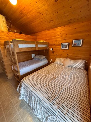 a bedroom with two beds in a wooden cabin at Bras D'Or Lakes Campground in Baddeck Inlet
