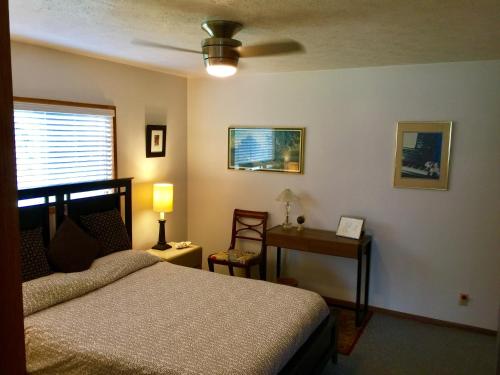 a bedroom with a bed and a table and a fan at Hale “Hā Hā” in Pahoa