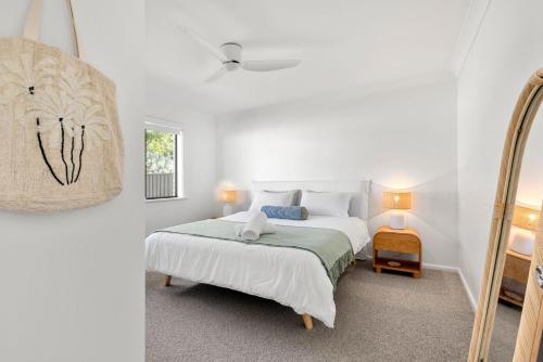 a white bedroom with a bed and a mirror at Coastline Callala - Fire Pit - Pet Friendly in Callala Beach