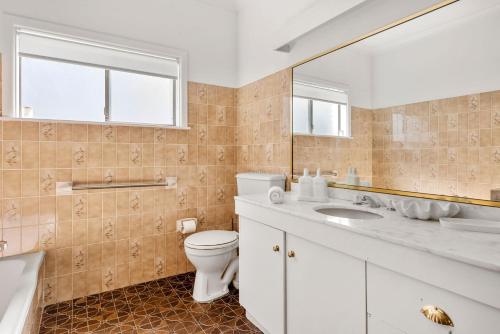 a bathroom with a toilet and a sink and a mirror at Coastline Callala - Fire Pit - Pet Friendly in Callala Beach