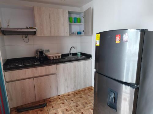 a kitchen with a stainless steel refrigerator and wooden cabinets at apartamento vacacional red in Salento