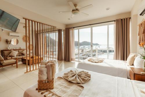 a hotel room with two beds and a large window at Suites La Playa in Santa Cruz Huatulco