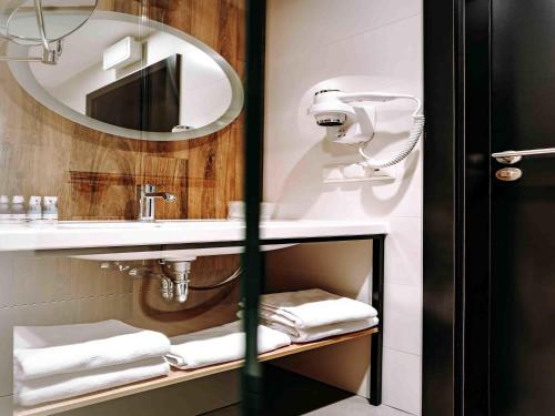 a bathroom with a sink and a mirror and towels at Hotel Mercure Toruń Centrum in Toruń