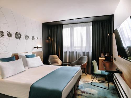 a hotel room with a large bed and a desk at Hotel Mercure Toruń Centrum in Toruń