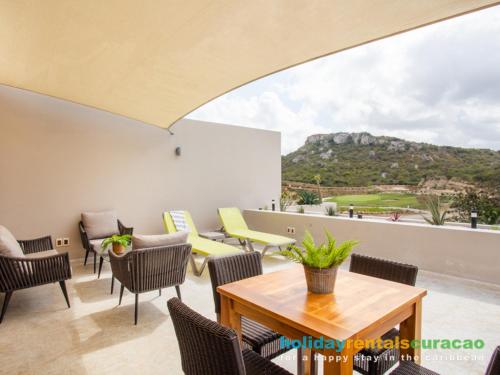 a patio with chairs and tables and a view of a mountain at Apartment 387 Blue Bay in Dorp Sint Michiel