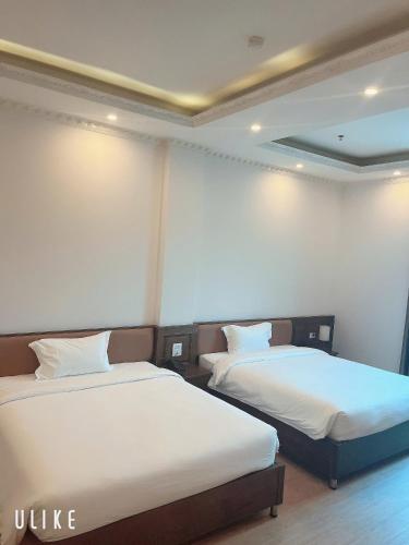 two beds in a hotel room with white sheets at Khách Sạn VizGoo in Bắc Ninh