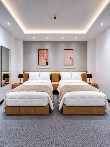 two beds in a large bedroom with two lamps at Hotel Arkam in San Salvador