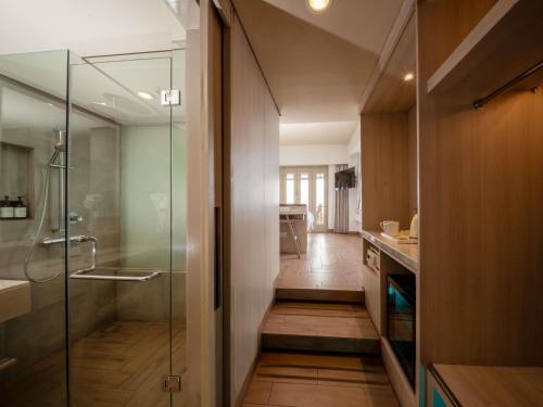 a bathroom with a walk in shower and a glass door at Mercure Kuta Bali in Kuta