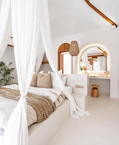 a white bedroom with a canopy bed with curtains at Belajar Bali Boutique Hotel and Retreat in Canggu