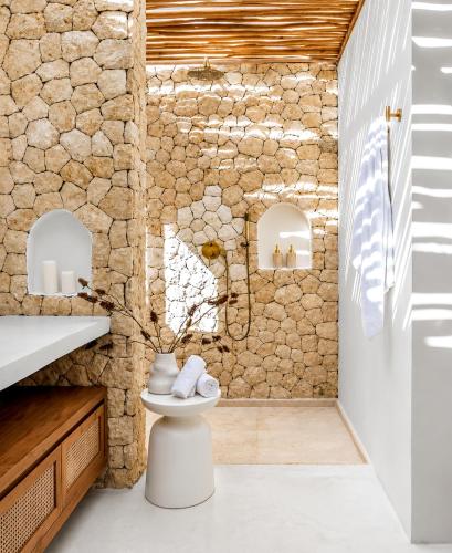 a bathroom with a toilet and a stone wall at Belajar Bali Boutique Hotel and Retreat in Canggu