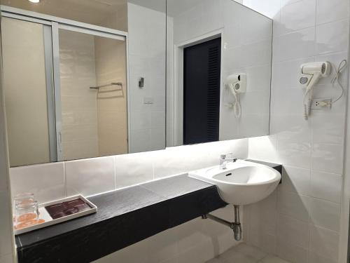 a white bathroom with a sink and a mirror at Baron Beach Hotel in Pattaya
