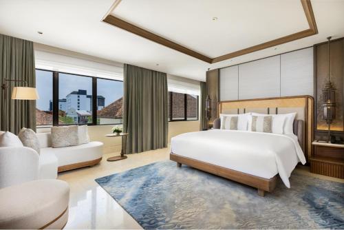 a bedroom with a large white bed and a couch at Grand Hotel De Djokja in Yogyakarta