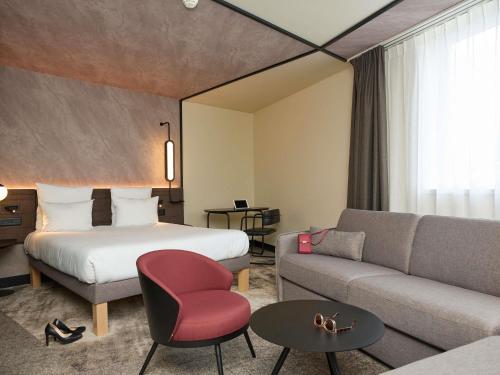 ein Hotelzimmer mit einem Bett und einer Couch in der Unterkunft Novotel Bern Expo in Bern