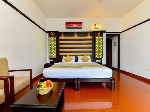 a bedroom with a bed and a table in a room at Mannath Ayur Island Resort in Murinjupuzha