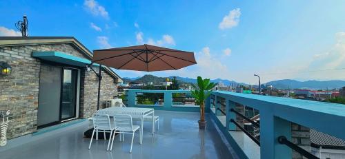 a balcony with a table and chairs and an umbrella at 뷰하우스 in Jeonju