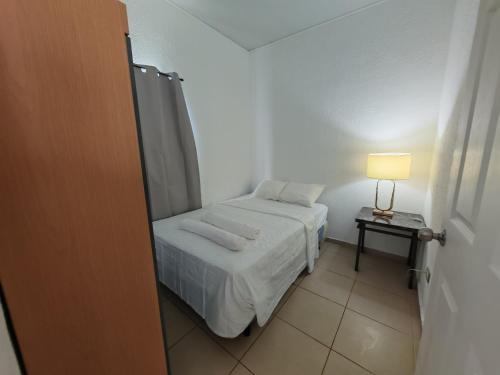 a small bedroom with a bed and a table with a lamp at Hermosa casa cerca de todo in Sitio del Niño