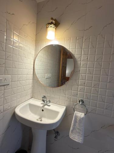 a white bathroom with a sink and a mirror at Enroot Manali in Vashisht