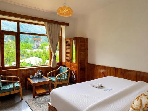 a bedroom with a bed and a table and chairs at Enroot Manali in Vashisht