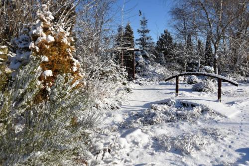 a snow covered park with a bridge and trees at Motel Paradise in Torzym