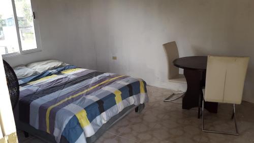 a bedroom with a bed and a desk and a table at Casa Ricky's in Orange Walk