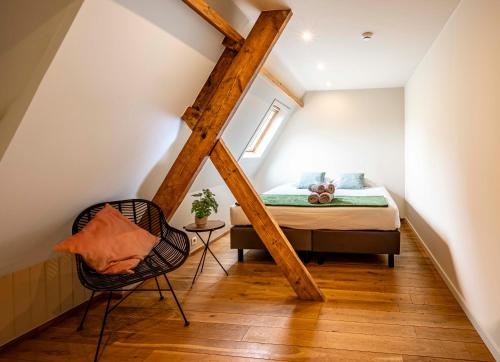 a small attic bedroom with a bed and a chair at Ryckevelde in Damme