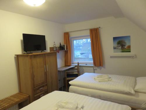 a hotel room with two beds and a television at Bredeneeker Gasthaus in Rastorf