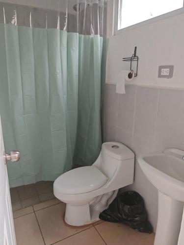 a bathroom with a white toilet and a sink at Hermosa casa con piscina in Sitio del Niño