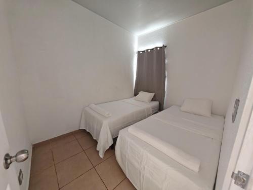a small white room with two beds in it at Hermosa casa con piscina in Sitio del Niño