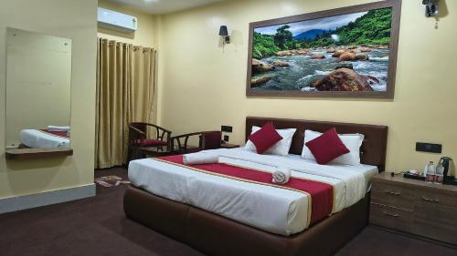 a bedroom with a bed with a painting on the wall at Maa Paradise World in Alīpur Duār