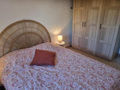a bed with a red pillow on top of it at Mini Villa 200 m de la plage in Cervione