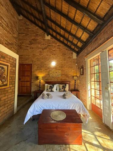a bedroom with a large bed in a brick wall at Bush and Gables in Marloth Park