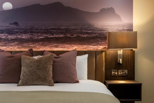 a bed with pillows and a picture of the ocean at Arden House in Dingle