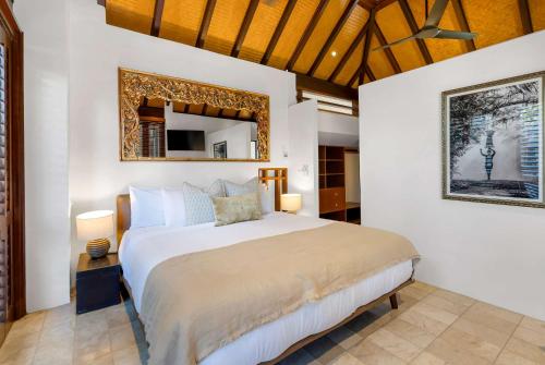 a bedroom with a bed and a mirror in it at Monsoon Villa A - Central Balinese-style Pool Oasis in Port Douglas