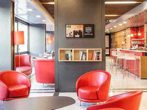 a restaurant with red chairs and a table and a counter at Ibis Roma Fiera in Rome