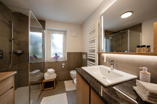 a bathroom with a sink and a shower and a toilet at Apartments Rezia in Ortisei