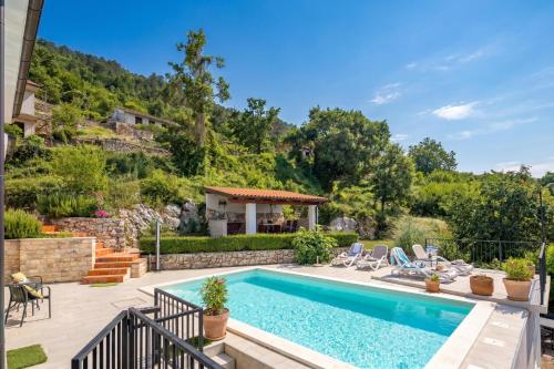 a swimming pool with chairs and a house at Hillside Villa Kvarner: Pool & Sea View - Happy Rentals in Ičići