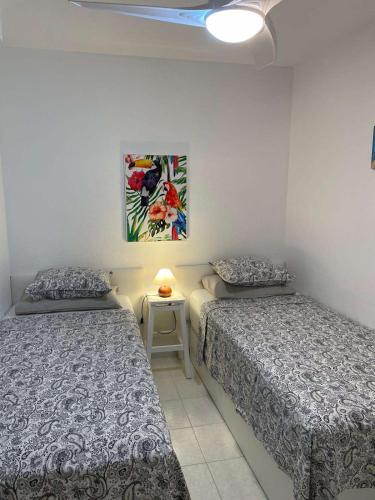 a bedroom with two beds and a table with a lamp at Anna Apartment in Altea