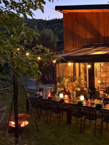 a long table with chairs and lights in a yard at Dom i Las in Brenna