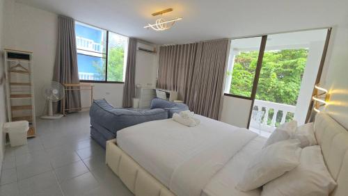 a bedroom with a large white bed and a couch at Chillax Townhome 65 in Hua Hin