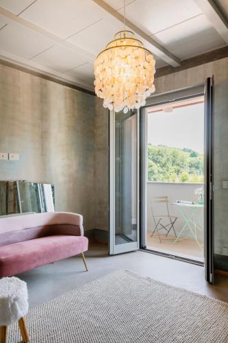 a living room with a pink couch and a chandelier at L'Attico di Asilo in Barolo in Barolo