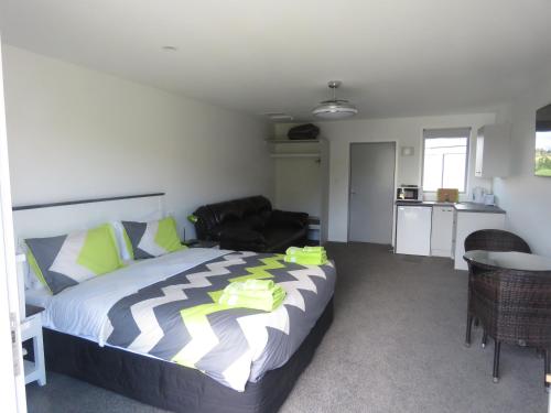 a bedroom with a bed and a couch and a kitchen at Cromwell Escape in Cromwell