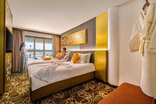 a hotel room with a large bed with a woman sitting at a desk at Sama-Sama Express KLIA Terminal 1 - Airside Transit Hotel in Sepang