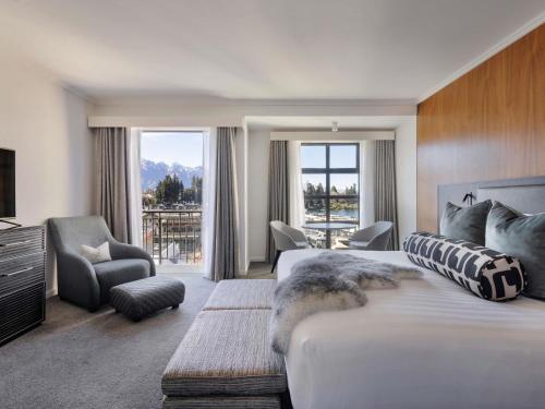 a hotel room with a large bed and a large window at Sofitel Queenstown Hotel & Spa in Queenstown